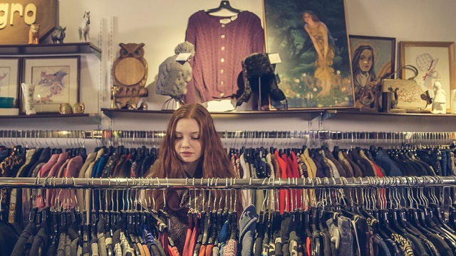 Žena si prezerá tovar v obchode s oblečením